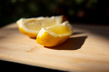 Two slices of ripe juicy lemon on a wooden board on a dark background