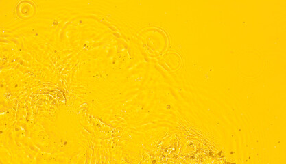 Abstract summer background. Transparent yellow clear water surface texture with ripples, splashes and bubbles. Top view