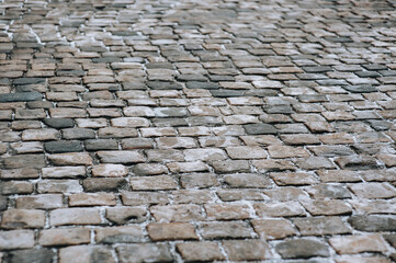 The gray paving stones close up. The texture of the old dark stone. Road surface with snow....