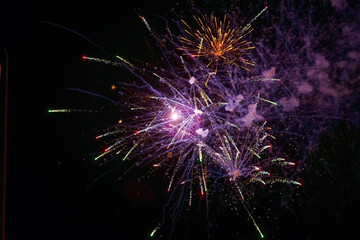 Bright and beautiful festive fireworks of yellow and lilac color, with haze, in the night sky