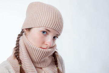 Pretty girl with blue eyes and wicker braids in a knitted hat and scarf