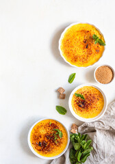 Creme brulee with caramel crust and mint in ceramic dishes. Famous french dessert. Delicious desserts for cafe or restaurant. Top view.