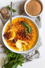 Creme brulee with caramel crust and mint in ceramic dishes. Famous french dessert. Delicious desserts for cafe or restaurant. Top view.