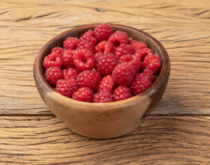Raspberries in a bowl over wooden table