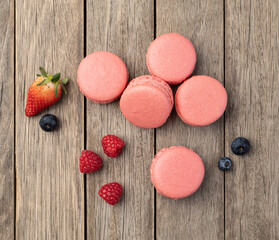 Berry macarons with strawberries, raspberries and blueberries over wooden table