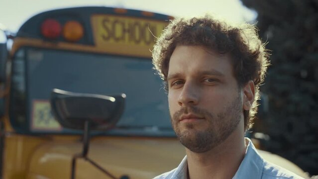 Closeup schoolbus chauffer face at vehicle. Handsome man driver looking camera.