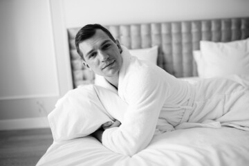 Fototapeta premium in the photo, a smug man in a bathrobe in hotels lying down enjoying the view from the window