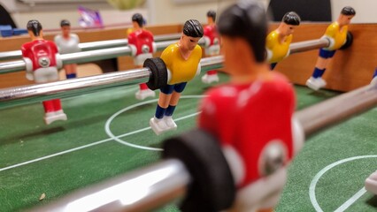 Fototapeta premium Players in a small table foosball game playing in Red and Yellow.