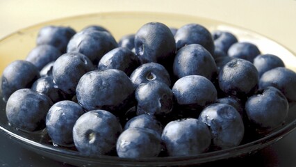 wild blueberries. Ecological product. Good for your health. Wild berry. Ingredient for jam. Berries on a glass saucer. Close-up. Object rotation. Grey background.