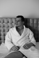 in the photo, a smug man in a bathrobe in hotels lying down enjoying the view from the window