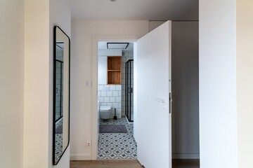 View from the hall to the entrance to the bathroom with a shower cabin and a toilet. Modern...