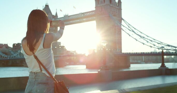 The back of a woman taking photos of Westminster bridge in London