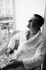 in the photo, a smug man in a bathrobe in hotels lying down enjoying the view from the window