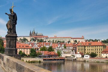 Obraz premium Charles bridge with statue of John the Baptist, Vltava river, Pague castle in a background.