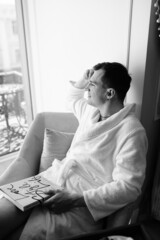 in the photo, a smug man in a bathrobe in hotels lying down enjoying the view from the window