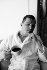 in the photo, a smug man in a bathrobe in hotels lying down enjoying the view from the window