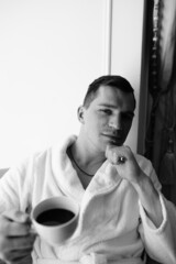 in the photo, a smug man in a bathrobe in hotels lying down enjoying the view from the window