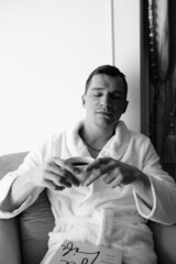 in the photo, a smug man in a bathrobe in hotels lying down enjoying the view from the window