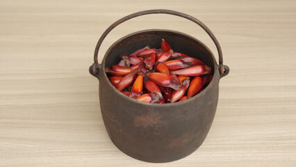 Black iron pan with pine nuts inside. Wood background. Traditional Brazilian winter food. Typical...
