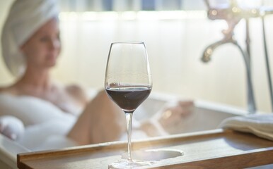 Obraz na płótnie Canvas Woman relaxing in bubble bath in bathtub drinking tasting red wine.