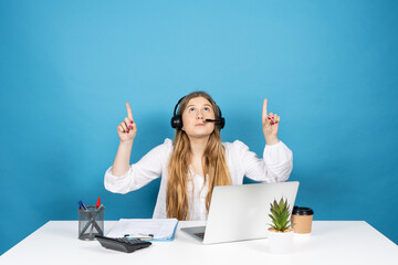 Telemarketing operator pointing above to copy space. Young virtual assistance worker isolated on blue background. - obrazy, fototapety, plakaty
