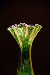 Yellow and green glass vase illuminated against a dark background