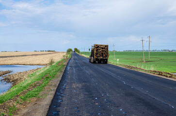 A tractor with a trailer on an asphalt road transports natural manure to the field. Use of organic fertilizers for environmentally friendly food.