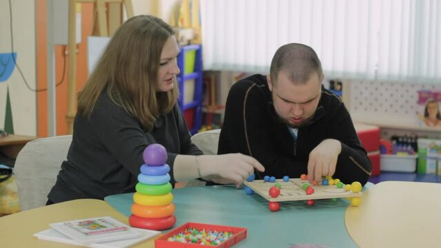 A female psychologist works with an adult boy with autism in the office. The concept of autism