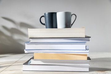 White and gray coffee cups on a stack of books. Home office concept, back to school