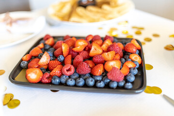 Sliced strawberries and blueberries on a dessert plate on the table during a birthday party