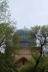 Blue tower of the Bibi-Khanym Mosque in trees - Samarkand, Uzbekistan