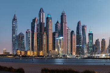 Fototapeta na wymiar Modern glass skyscrapers in Dubai with blue sky in background. Impressive architecture of financial district and Dubai marina. 