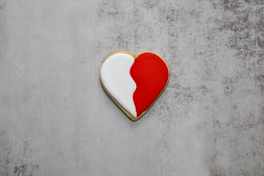 A two tone heart shape sugar cookie with red and white royal icing.