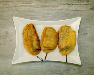 Top view of three chile rellenos on a white platter. 