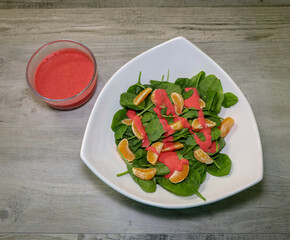 A healthy spinach salad with mandarin oranges and raspberry vinaigrette dressing.