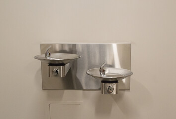 Two drinking water fountains on a wall inside a building.