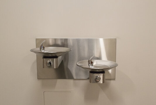 Two drinking water fountains on a wall inside a building.