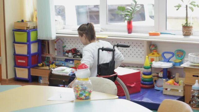 a girl with disabilities moves around the room in a wheelchair