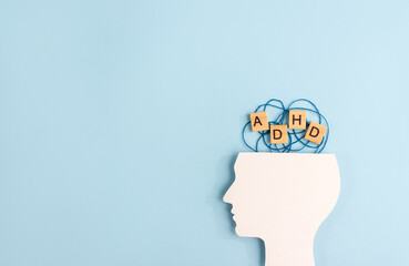 Silhouette of human head and wooden blocks with the letters ADHD on pastel background. Creative concept of attention deficit hyperactivity syndrome. Copy space - obrazy, fototapety, plakaty