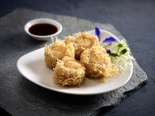Crispy fried Yam Ring stuffed with Scallop served in a dish isolated on wooden board side view dark background