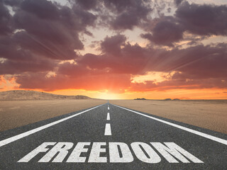 Freedom word on a road leading into the distance for happiness concept.