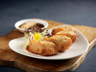 Crispy Dough Fritters stuffed with Seafood Paste served in a dish isolated on wooden board side view dark background