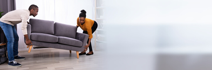 Obraz premium Couple Lifting Sofa In Living Room