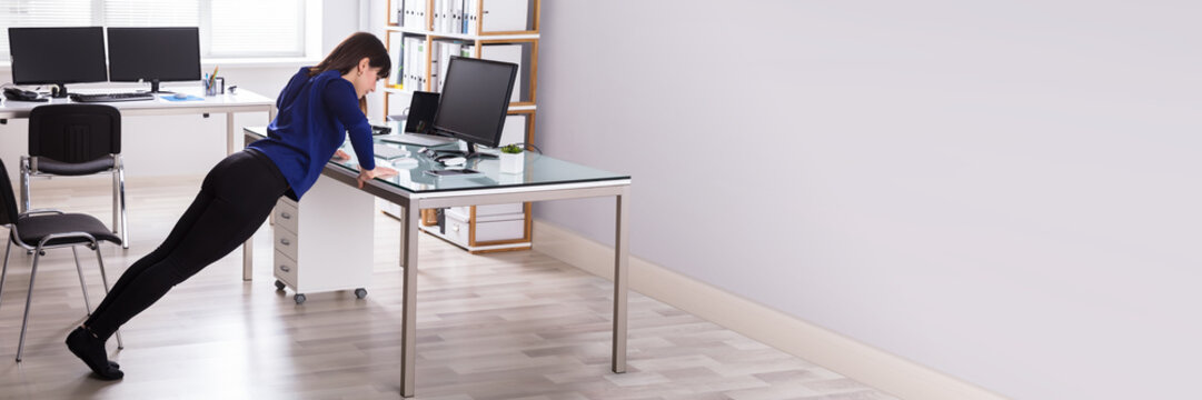 Businesswoman Doing Push Up On Office Desk