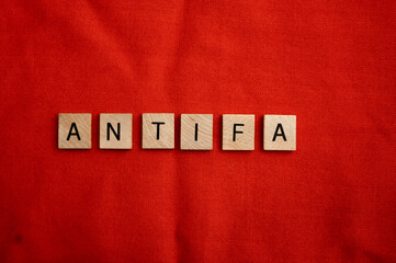 ANTIFA concept with wooden tile letters on a red background.