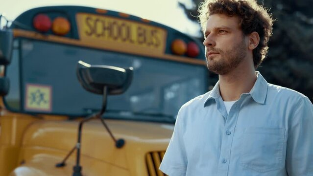Portrait car driver stand near yellow school bus. Serious man looking camera.