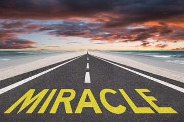 The word Miracle on a beacutiful road at the beach leading to the sunset.