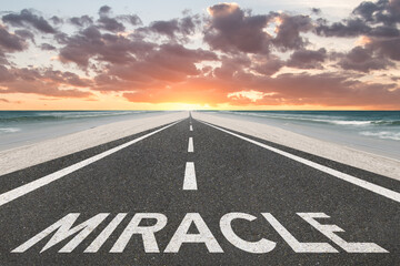 The word Miracle on a beacutiful road at the beach leading to the sunset.