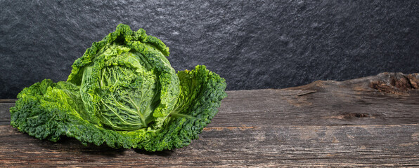 Raw, fresh savoy cabbage on wooden background, rustic concept