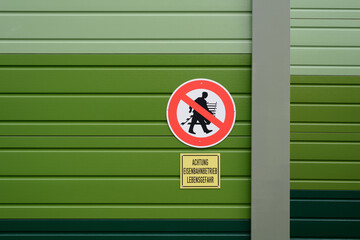 Verbotsschild Gleise überqueren an grüner Lärmschutzwand